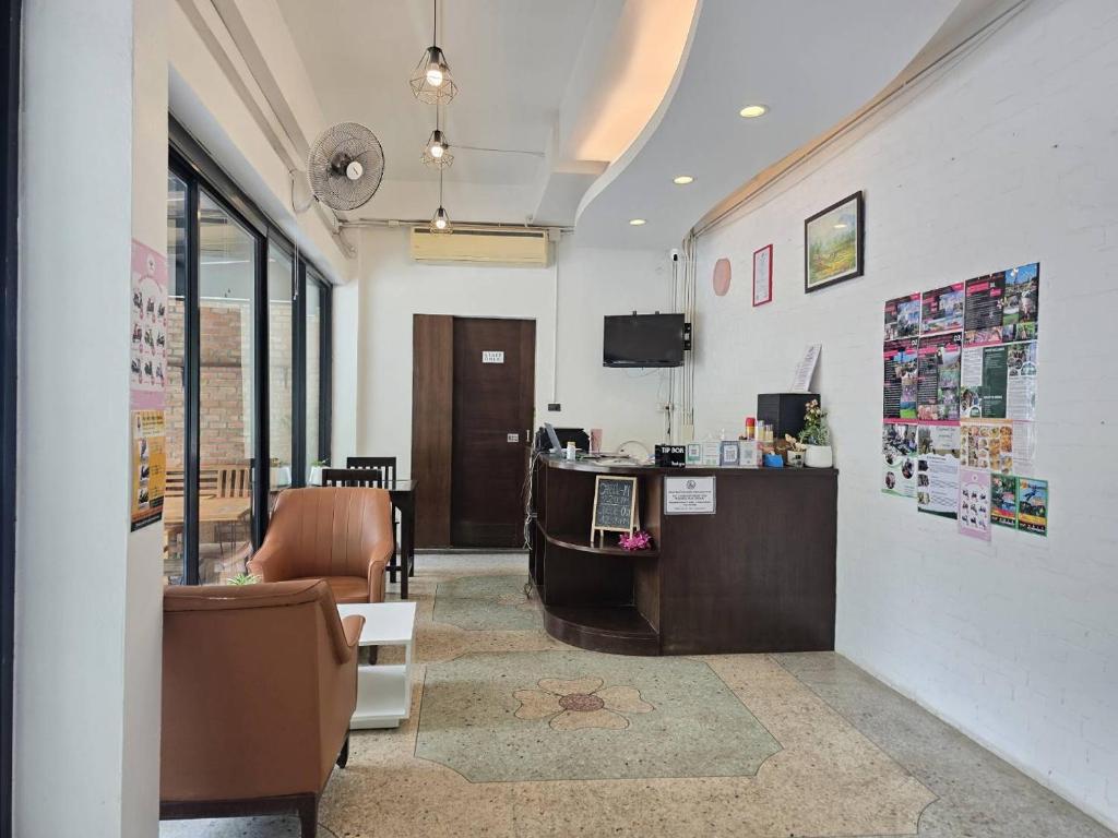 A compact reception area includes a front desk, lounge chairs, and a wall-mounted television.