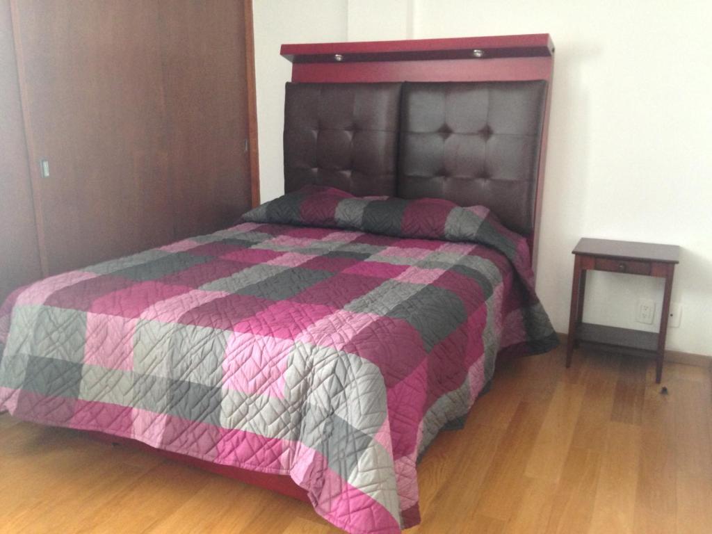 um quarto com uma cama com uma colcha rosa e cinzenta em Beautiful, down-town em Cidade do México