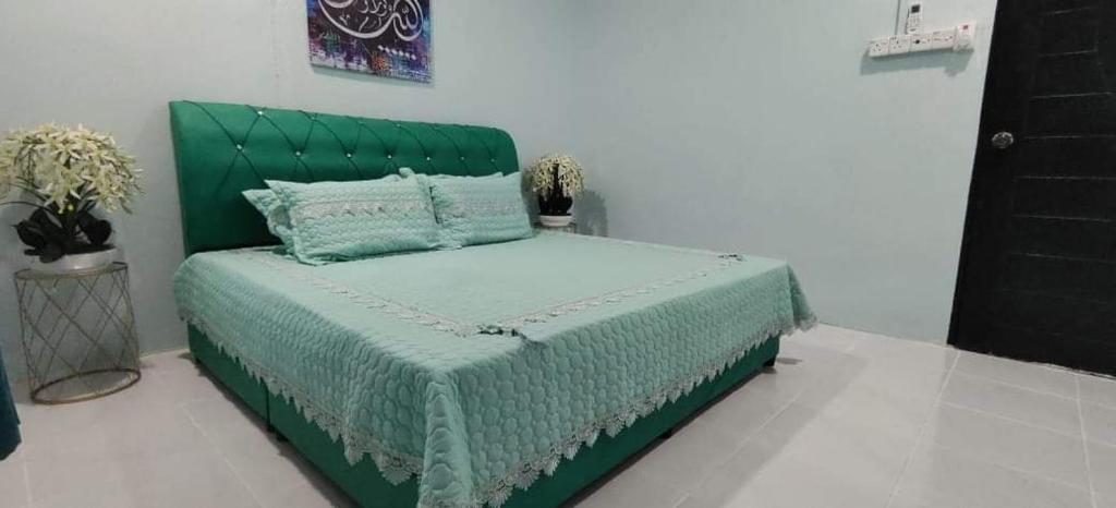 a bed with a green headboard in a room at Tasik Biru Homestay Kuala Terengganu in Marang