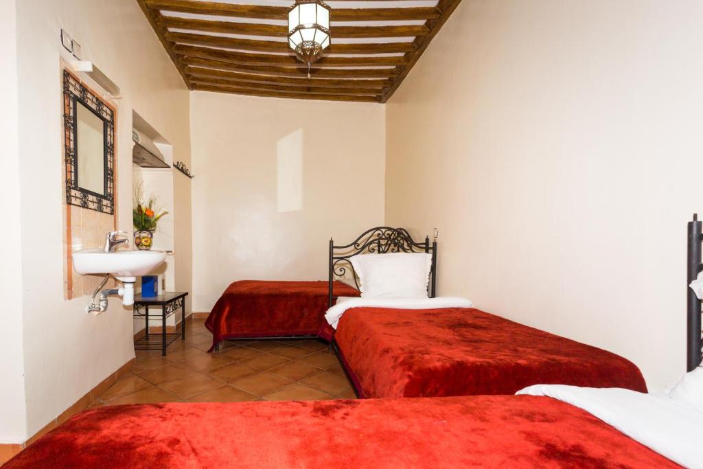 Un dormitorio con 2 camas y un lavabo en una habitación. en Hotel Atlas, en Marrakech