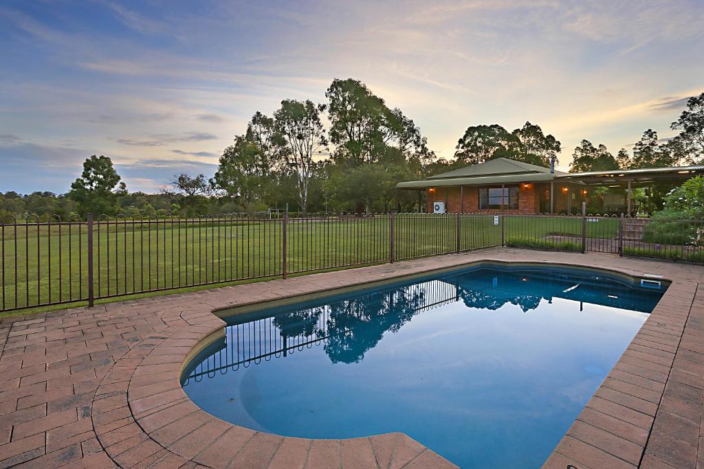 een zwembad in een tuin met een hek bij Hunter Valley Vineyard Large Family Farm Houses - Ironstone Estate Lovedale in Lovedale