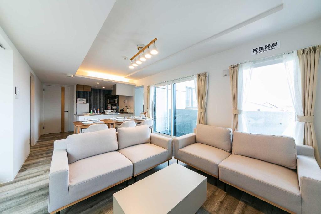 a living room with two couches and a kitchen at Twinberry CHITOSE in Chitose