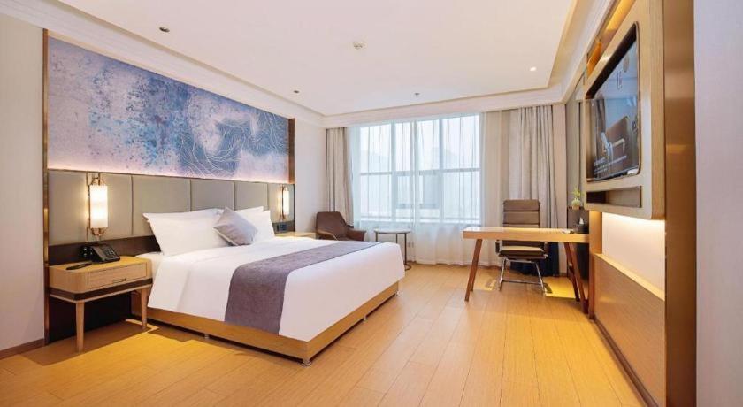 a hotel room with a bed and a desk and a television at GreenTree Inn Taiyuan PinGYAng Road Business Hotel in Taiyuan