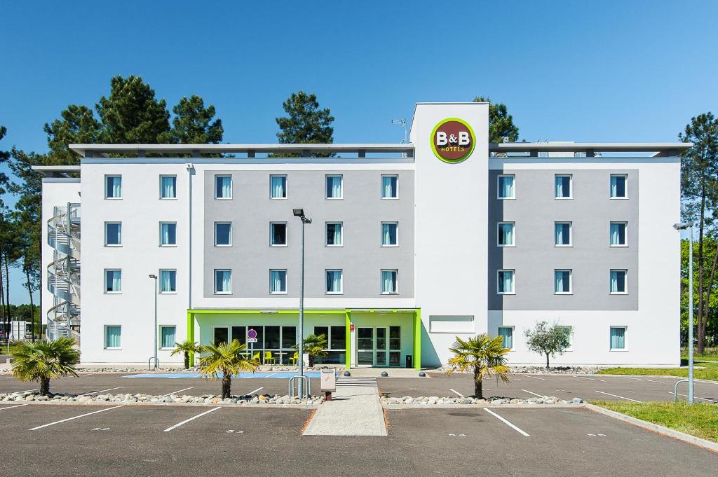 un edificio blanco con un cartel en un estacionamiento en B&B HOTEL Mont-de-Marsan en Saint-Avit