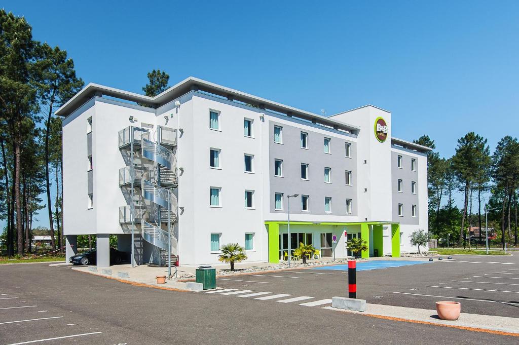 a large white building with a staircase in a parking lot at B&B HOTEL Mont-de-Marsan in Saint-Avit