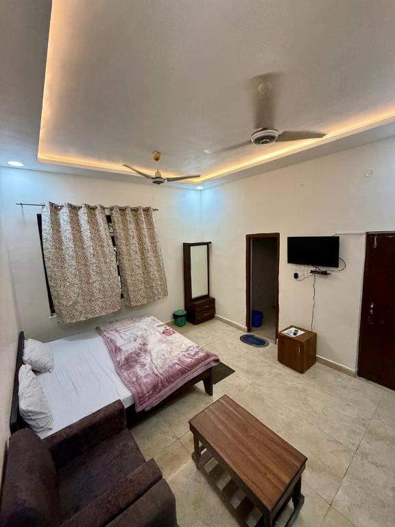 a bedroom with a bed and a couch and a table at KRISHNAM GUEST HOUSE in Gwalior