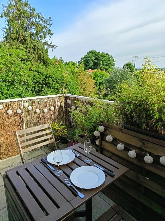 - une table en bois avec des assiettes sur la terrasse dans l'établissement Studio Bayonne proche gare et centre-ville, à Bayonne
