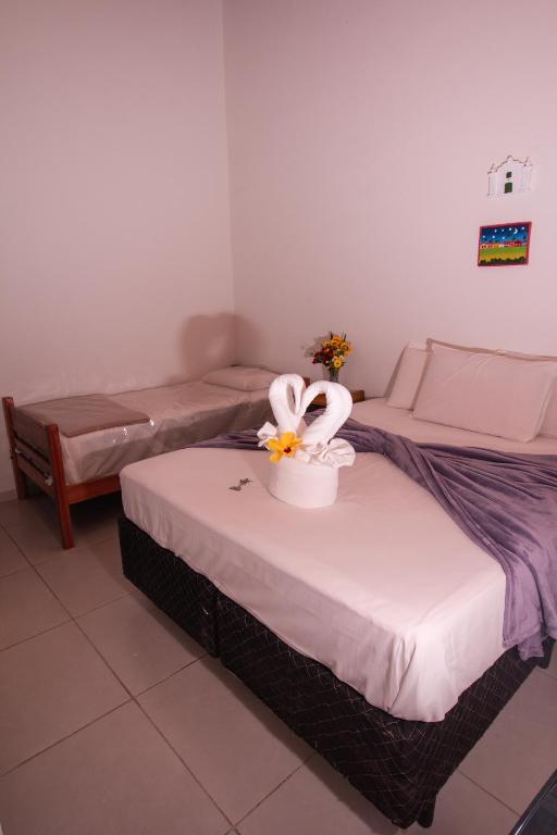 a room with two beds with a flower in a bucket at Pousada do Mineiro in Trancoso