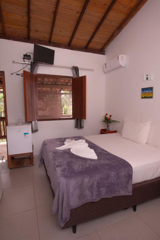 a bedroom with a bed with a tv on the wall at Pousada do Mineiro in Trancoso