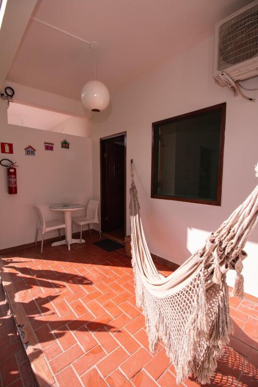 a hammock in a room with a television and a table at Pousada do Mineiro in Trancoso