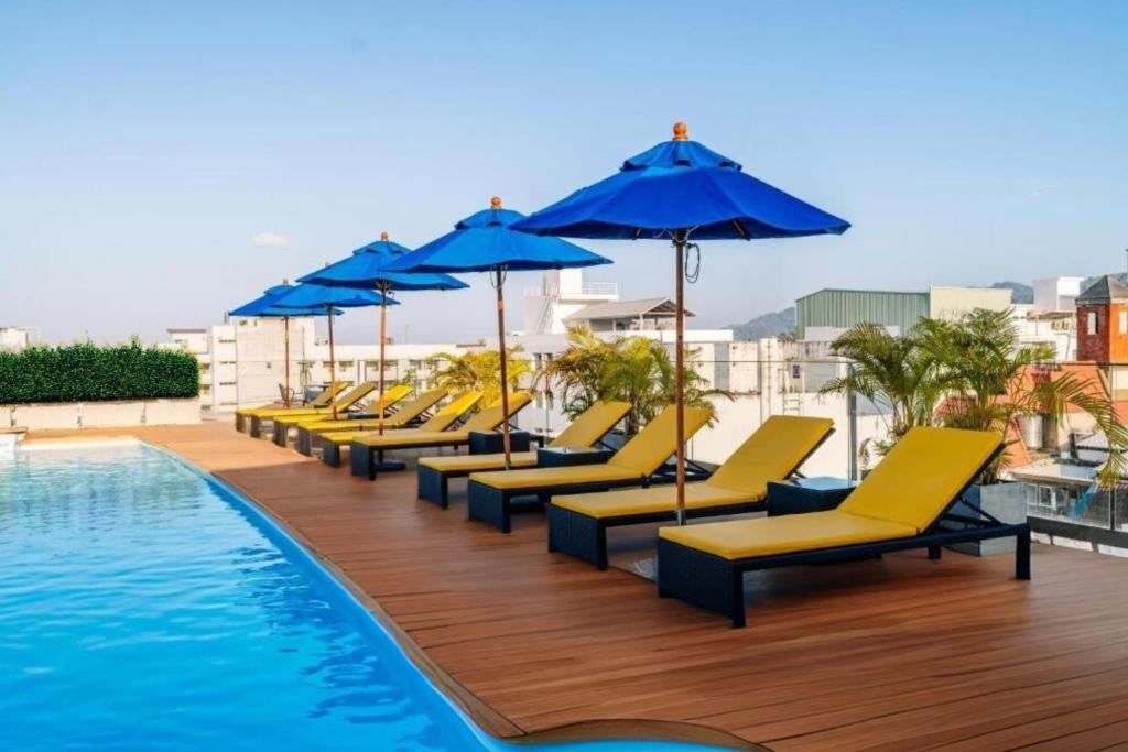 a row of yellow lounge chairs and umbrellas next to a pool at Days Inn by Wyndham Patong Beach in Patong Beach