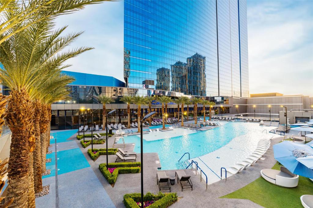 ein Pool mit Stühlen und Palmen und ein hohes Gebäude in der Unterkunft Hilton Club Elara Las Vegas in Las Vegas