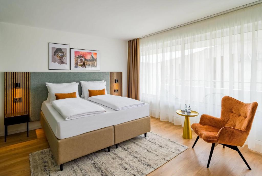 a bedroom with a bed and a chair at Aspire Palais Recklinghausen, Trademark Collection by Wyndham in Recklinghausen