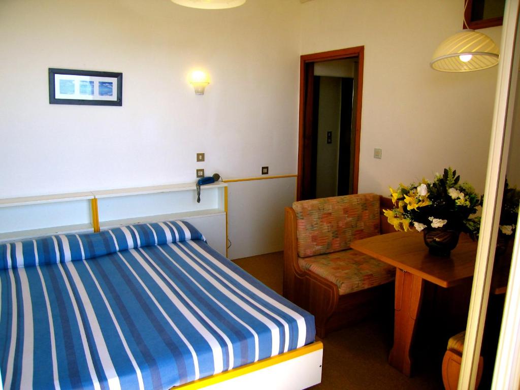 ein Schlafzimmer mit einem Bett, einem Stuhl und einem Tisch in der Unterkunft Mon Repos in Lido di Jesolo