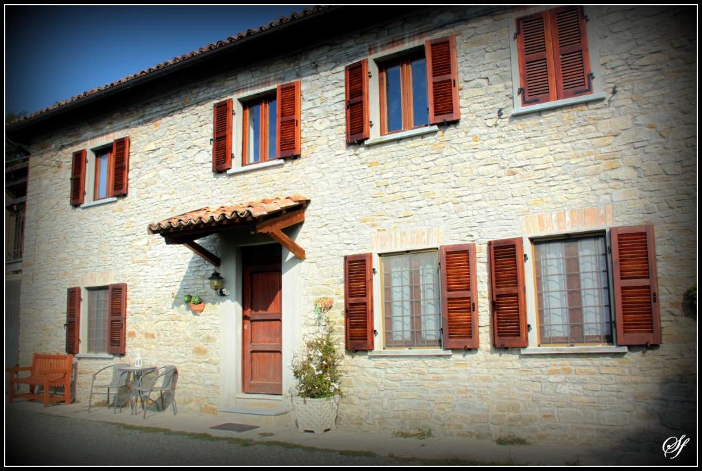 Castel BoglioneにあるBed and Breakfast Val d'Ocheの赤いシャッター付きの窓、テーブルと椅子が備わる建物