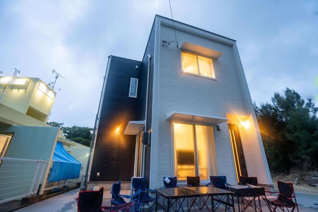 a house with chairs and a table in front of it at 家族の笑顔 笑顔があふれる体験を 沖縄一棟貸しのお宿 Coral Onnason in Onna