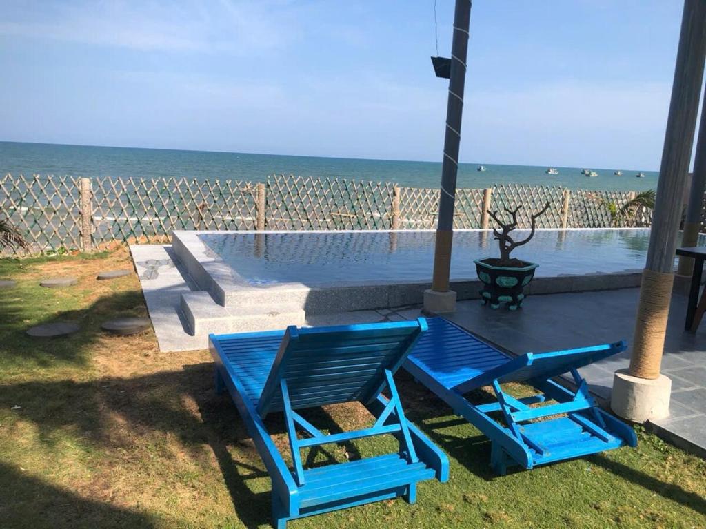 two blue chairs sitting on the grass near the ocean at Homestay Lac Long Quan by the Sea in Bình Sum