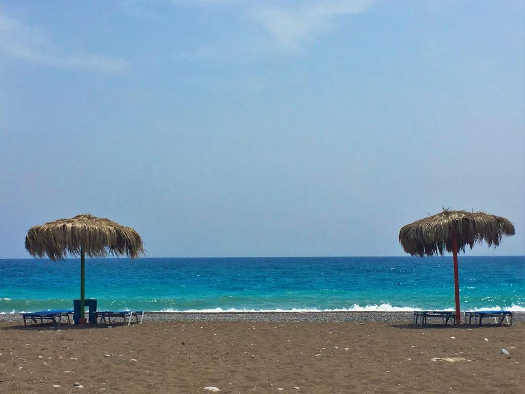 two chairs and umbrellas on a beach with the ocean at Mojito Beach Rooms in Lakhania