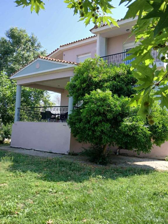 a house with a balcony with a tree in front of it at Maisonette Mangana in Xanthi