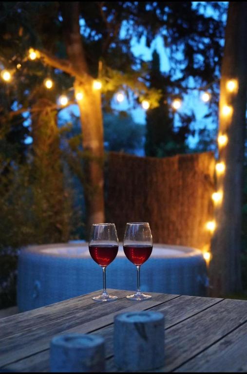 two glasses of red wine sitting on a wooden table at Essencia, gîte dans les collines de Toulon in Toulon