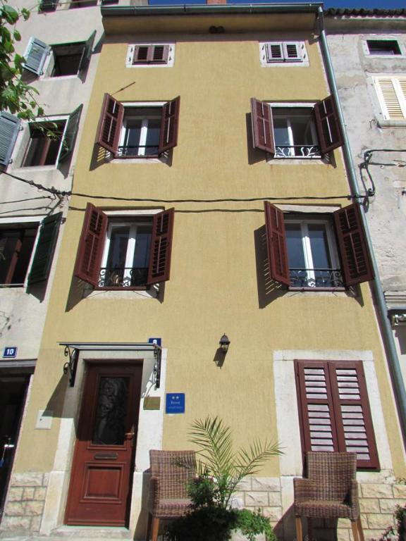 un edificio con puertas marrones, ventanas y sillas en Guesthouse Galeb, en Vrsar