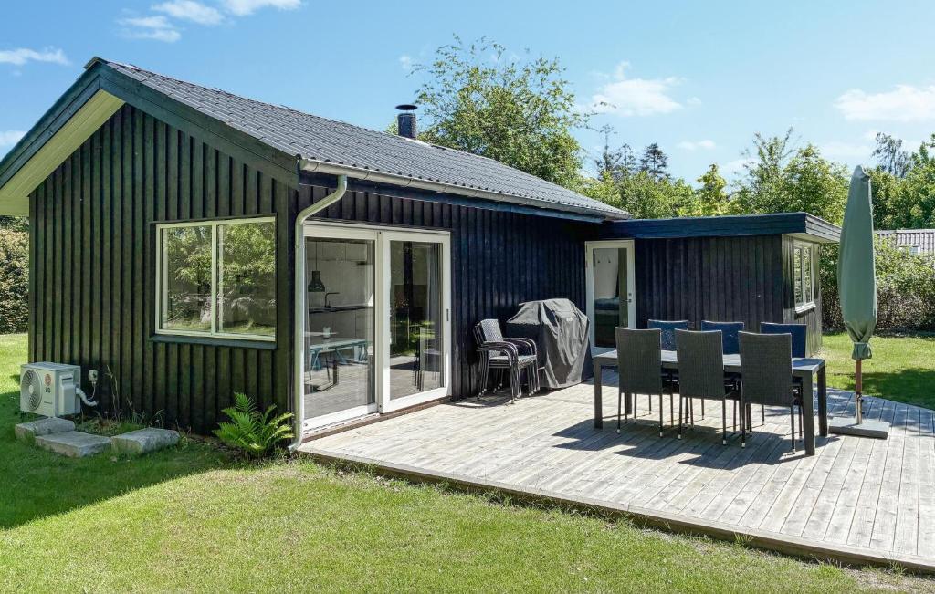 un hangar noir avec une terrasse avec des chaises et une table dans l'établissement 2 Bedroom Stunning Home In Væggerløse, à Bøtø By