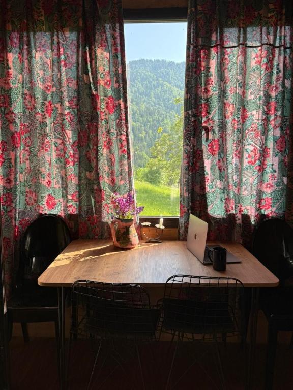a table with a laptop on it in front of a window at Welcome to Tamara Cottage in Tba