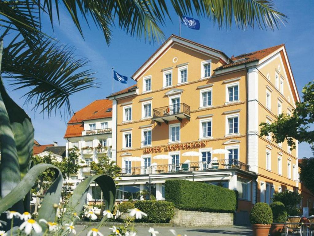 a large yellow building with two flags on it at Hotel Reutemann-Seegarten in Lindau