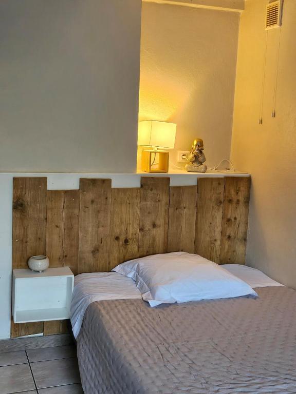 un lit avec une tête de lit en bois dans une chambre dans l'établissement Studio, à Vic-en-Bigorre