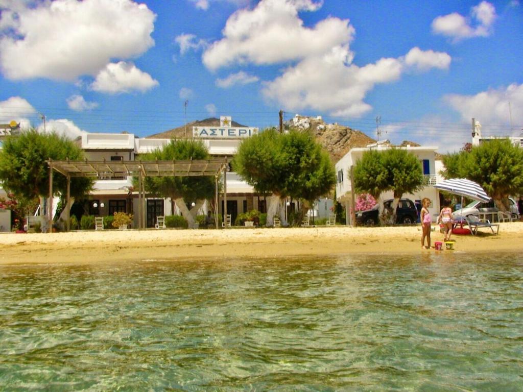 a group of people standing on a beach near the water at Asteri Hotel in Livadi