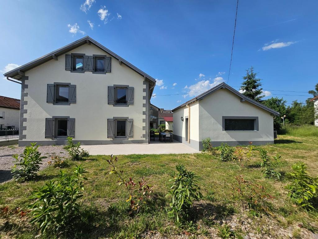 une maison blanche avec des fenêtres noires dans une cour dans l'établissement L'Escargot - Maison avec espace bien être, à Vagney