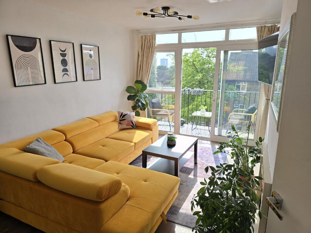 een woonkamer met een gele bank en een groot raam bij Beautiful 3-bed apartment at Swiss Cottage in Londen
