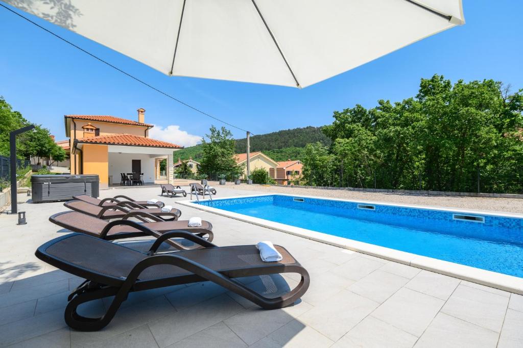 a swimming pool with lounge chairs next to a house at Villa Laura by Briskva in Ripenda Kras