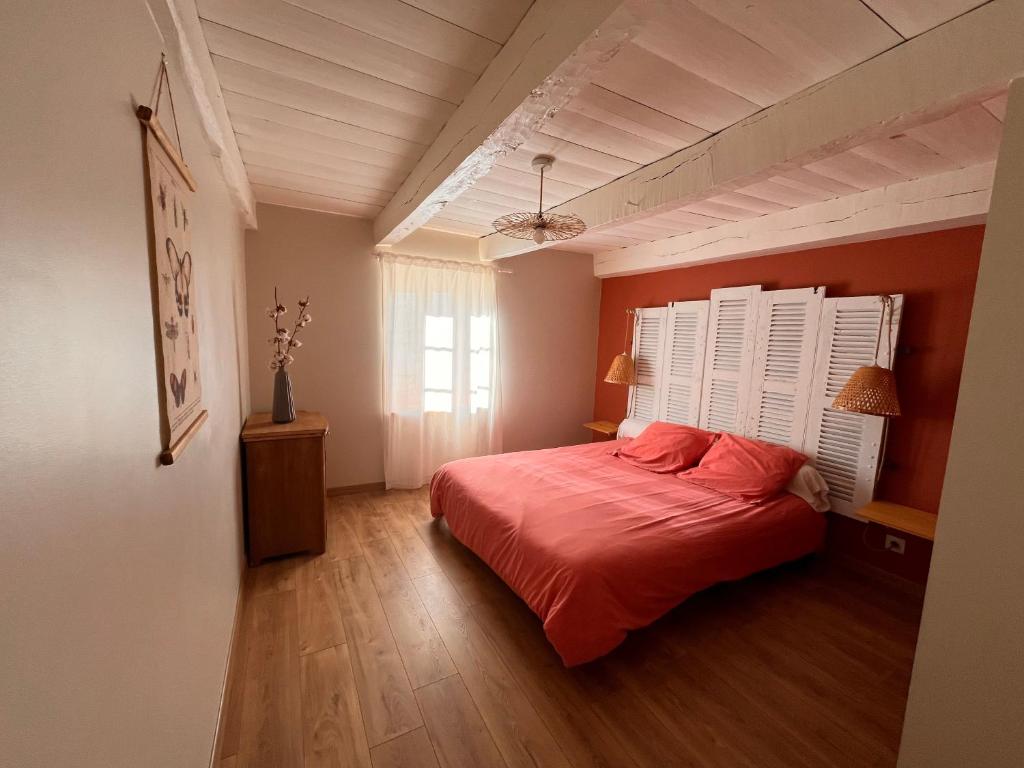 una camera da letto con un letto con lenzuola rosse e una finestra di Ti ar Goanag, Maison de vacances, Séjour, Week-end a Pleyben