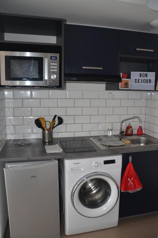une cuisine avec un lave-linge et un micro-ondes dans l'établissement L'escale phare, à La Rochelle
