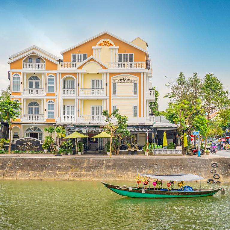 a boat in the water in front of a large building at Truc Loc Villa in Hoi An