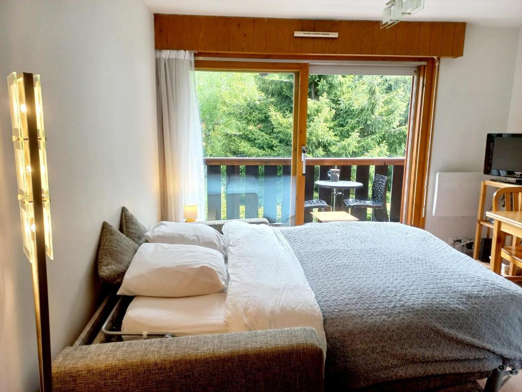 une chambre avec un grand lit avec une grande fenêtre dans l'établissement Sur le T M B centre village studio lumineux, aux Contamines-Montjoie
