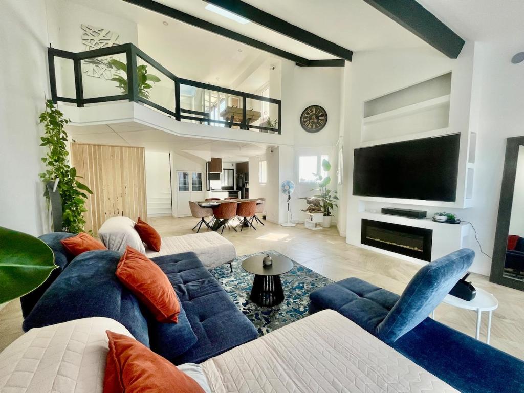 a living room with a blue couch and a tv at Penthouse de 170m2, 6 personnes avec jacuzzi et proche de Paris et Disney in Neuilly-sur-Marne