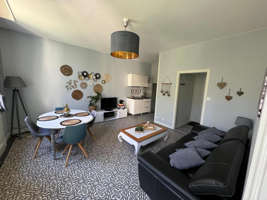 un salon avec un canapé noir et une table dans l'établissement Appartement dans le Beaujolais, à Villefranche-sur-Saône