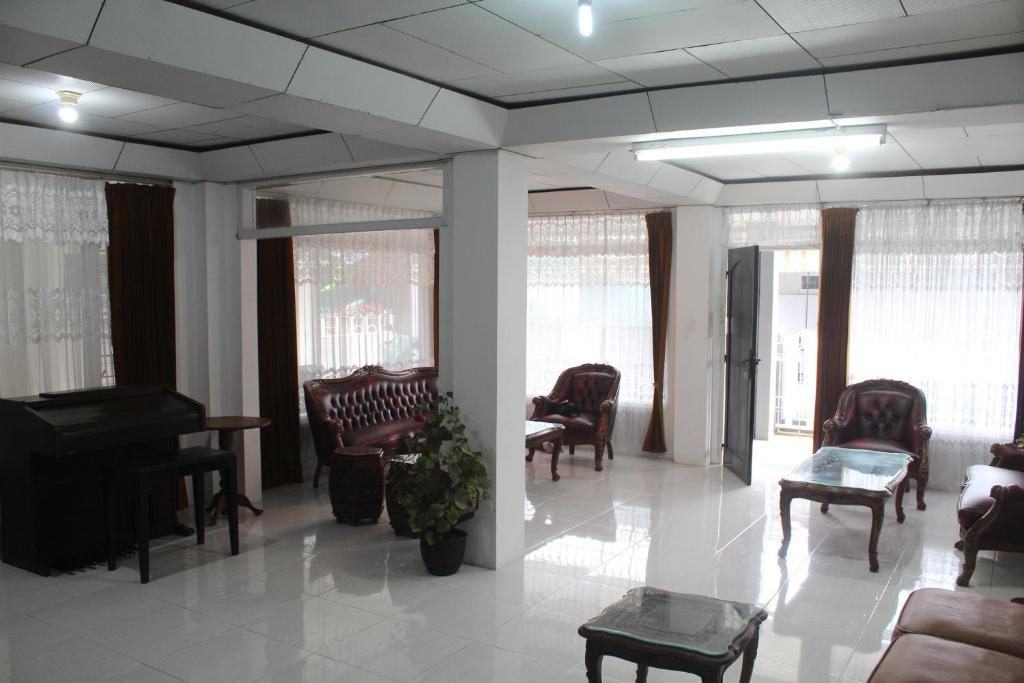 a waiting room with a piano and chairs and a table at Rumah Mama Homestay Syariah in Bukittinggi