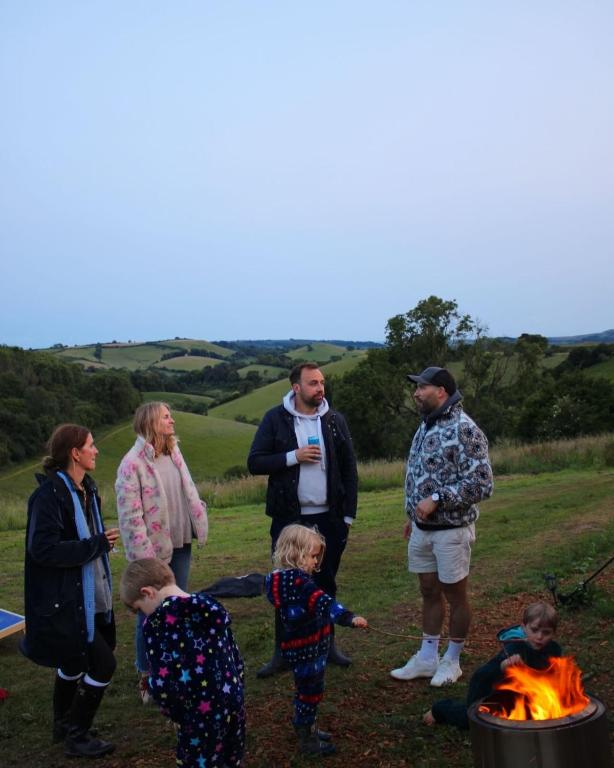 a group of people standing around a fire at Hidden Valley Dorset in Powerstock