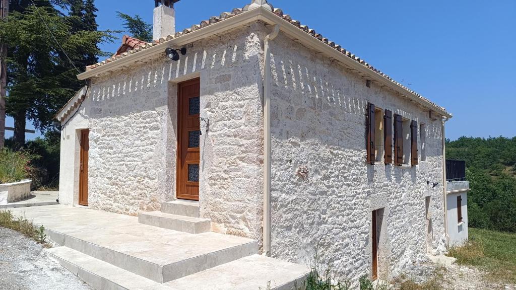 a small stone house with a wooden door and stairs at la maison de pejusclat in Villesèque