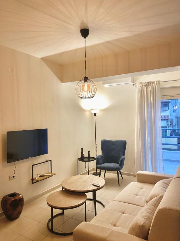 a living room with a couch and a tv at Ifigeneia Infinity Suites in Néa Alikarnassós