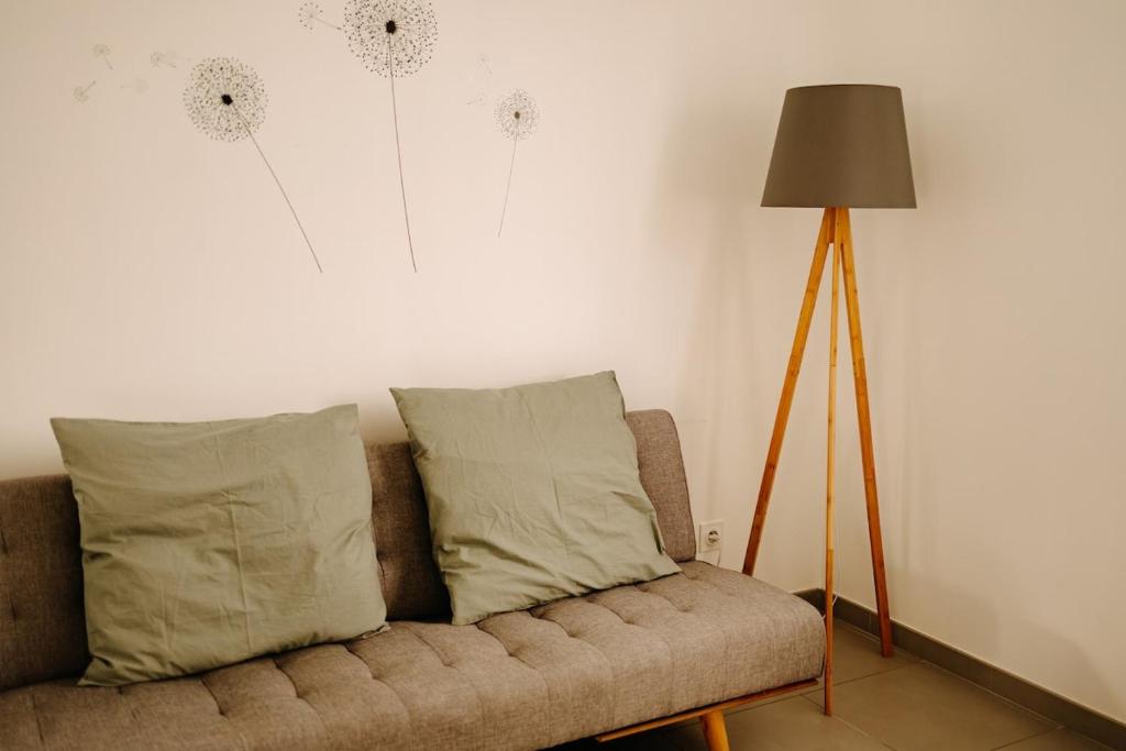 un canapé avec deux oreillers assis à côté d'une lampe dans l'établissement Le Carpe Diem, à Fiquefleur-Équainville