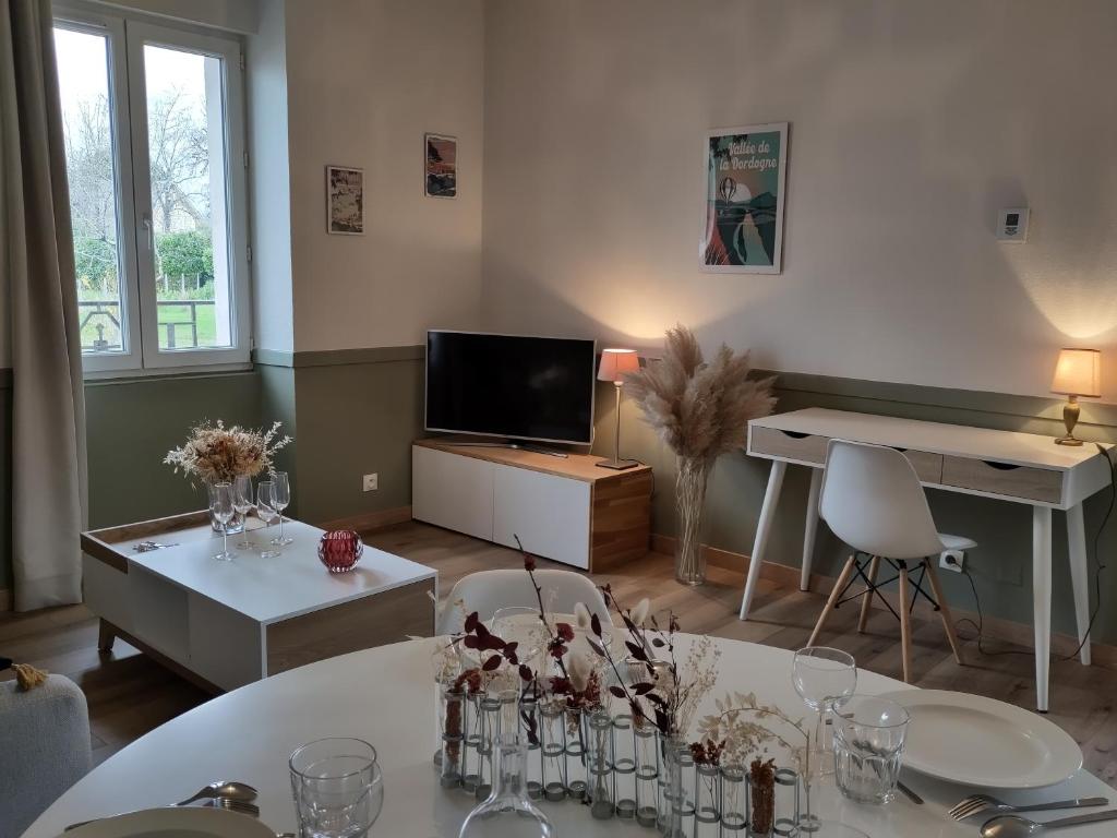 a living room with a table and a television at Appartement cosy avec Jardin clôturé in Bretenoux