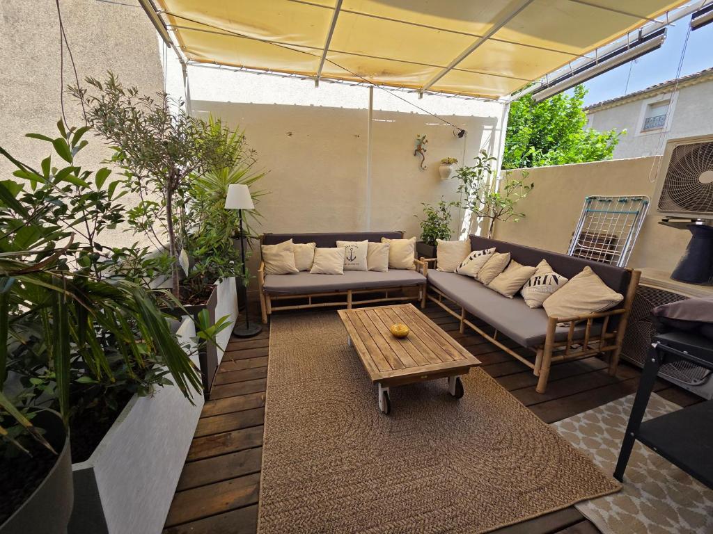 une terrasse avec un canapé et une table dans l'établissement Maison de ville standing proche mer, à Florensac