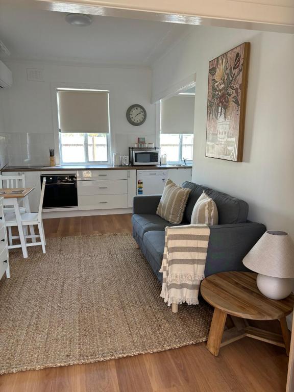 a living room with a blue couch and a kitchen at Eliza's Place - CWA Coonamble in Coonamble