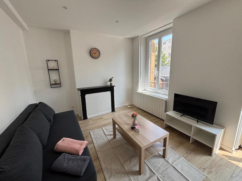 un salon avec un canapé noir et une table dans l'établissement City Break T2, à Clermont-Ferrand