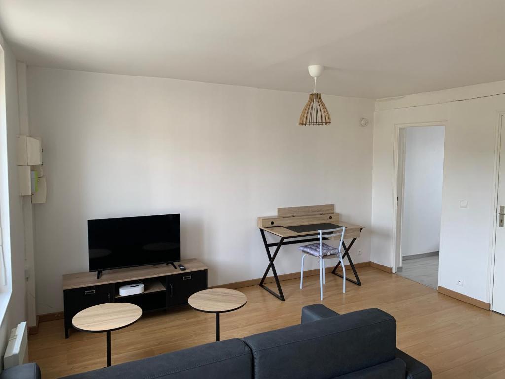 un salon avec un canapé, une table et une télévision dans l'établissement Charmant T2 meublé, à Saint-Laurent-en-Caux