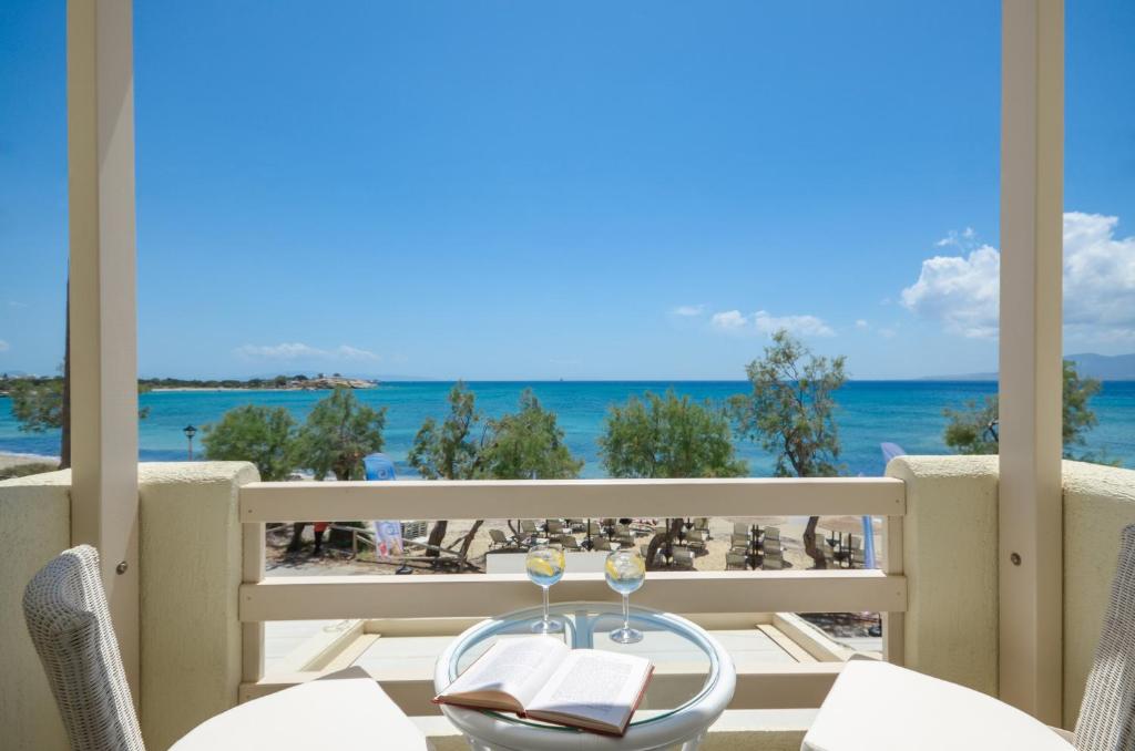 a table with wine glasses on a balcony with a view of the ocean at Angel Suites in Agia Anna Naxos